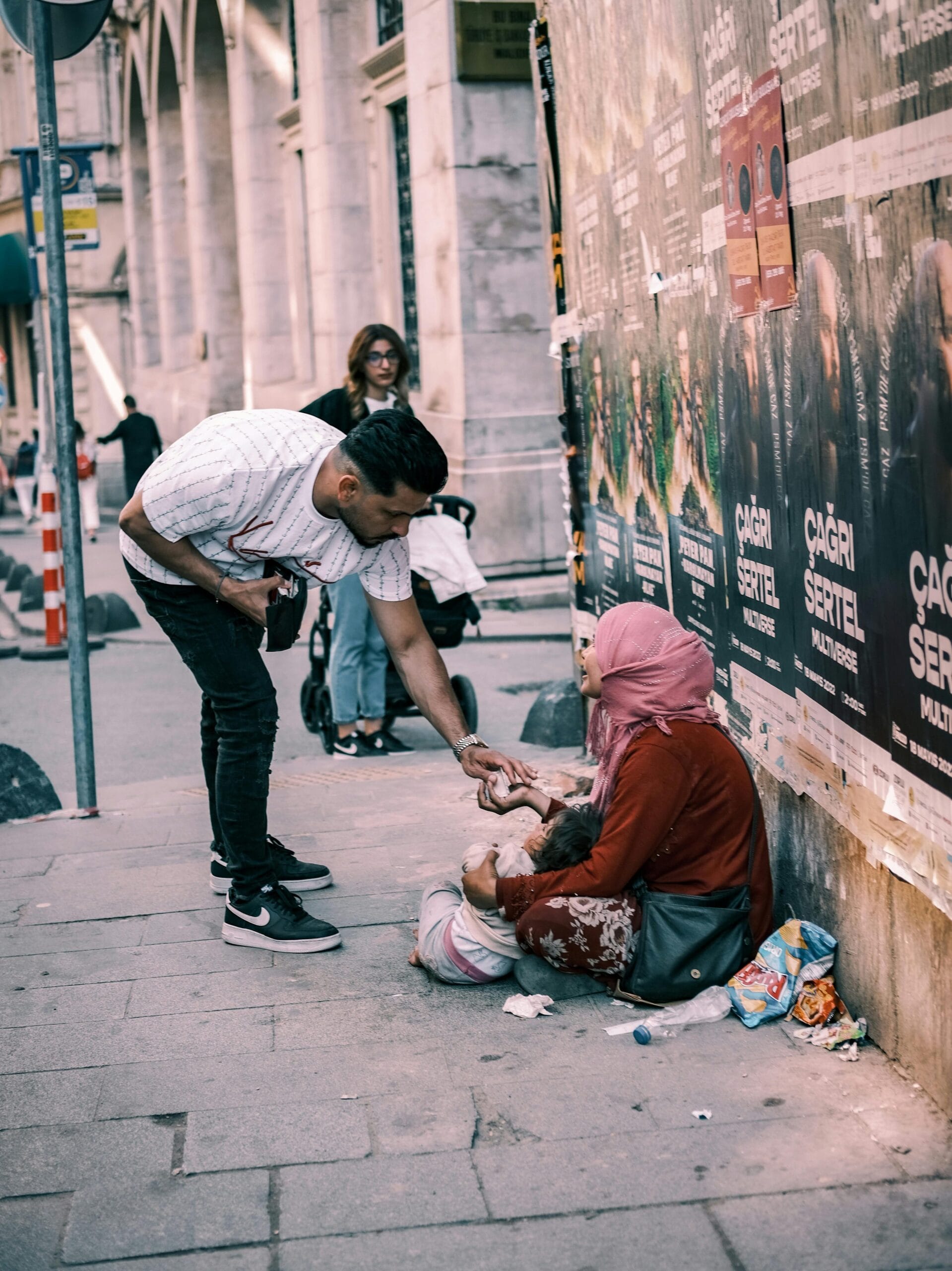 A man giving to a homeless woman on an Istanbul street, capturing urban generosity.