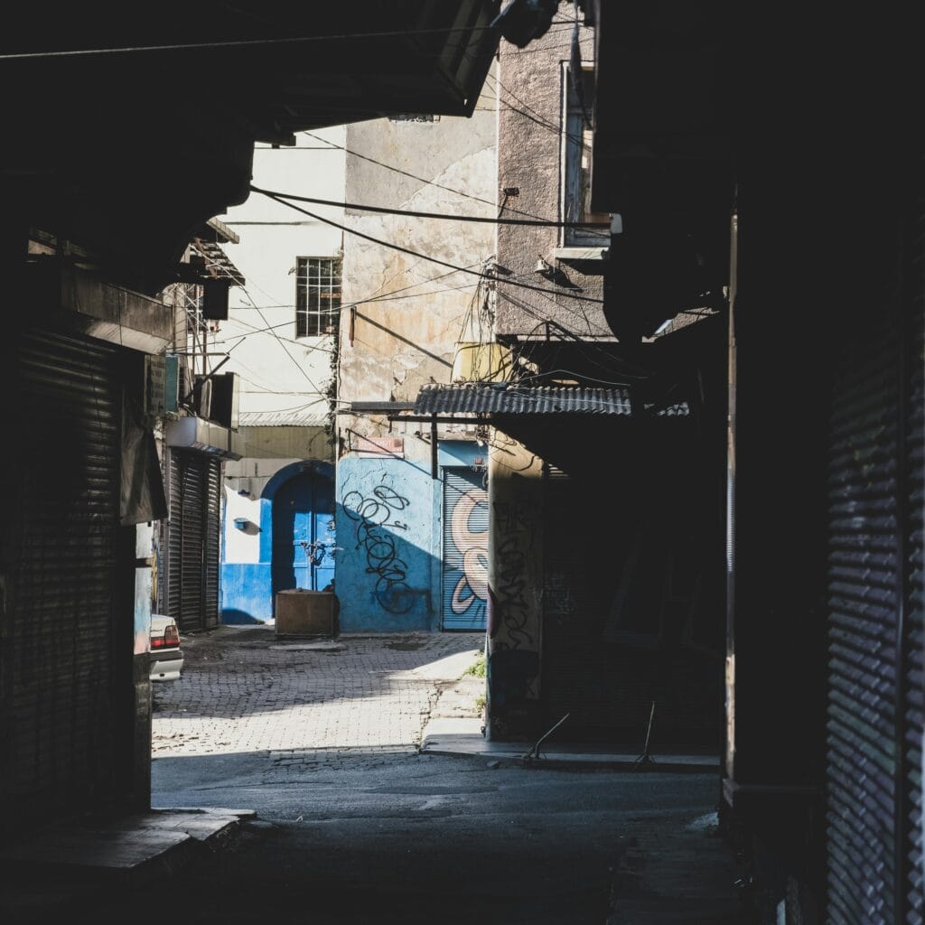 A rustic urban alley bathed in sunlight featuring vibrant graffiti art on the walls.